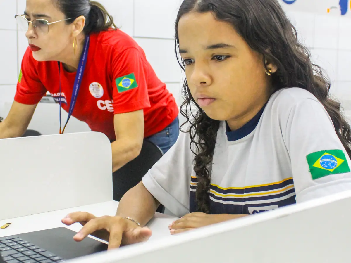 Professora acompanhando uma estudante do CEV Colégio Sul no notebook